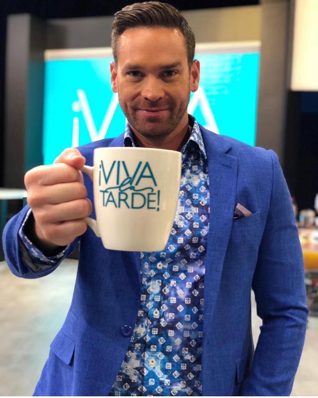 Man in a blue blazer and patterned shirt holding a mug